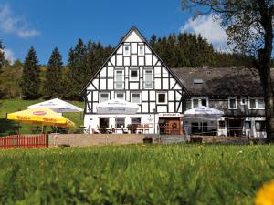 ein großes weißes Haus mit Sonnenschirmen davor in der Unterkunft Hotel & Restaurant Forellenhof in Bad Berleburg