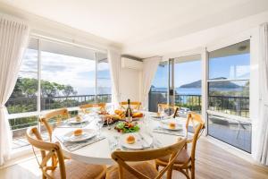 - une salle à manger avec une table, des chaises et de grandes fenêtres dans l'établissement Albacore 6, à Nelson Bay