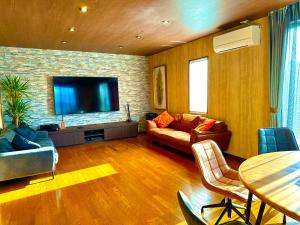 a living room with a couch and a flat screen tv at itotoi別邸-サウナ&プール&広々ドッグラン付きペットと泊まれる極上ヴィラ in Itoshima
