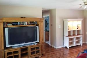 un salon avec une télévision sur un centre de divertissement en bois dans l'établissement White Squirrel Cottage, à Crawfordville