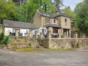 una antigua casa de piedra con un muro de piedra en Highwood Lodge, en Huddersfield