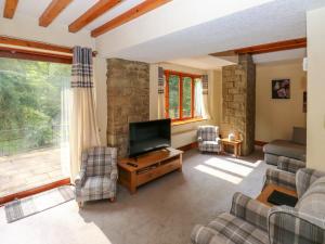 sala de estar con TV de pantalla plana y sillas en Highwood Lodge, en Huddersfield