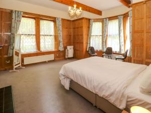 1 dormitorio con 1 cama, 2 sillas y ventanas en Highwood Lodge, en Huddersfield