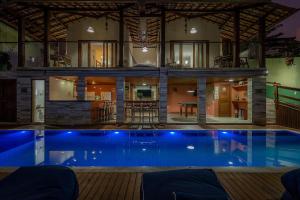 a house with a swimming pool at night at Villa Maritaca Condomínio de 4 Casas de Locação por Temporada de Alto Padrão com SPA in Arraial d'Ajuda