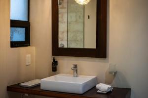 een badkamer met een witte wastafel en een spiegel bij KAHATSA' boutique hotel in Tulum