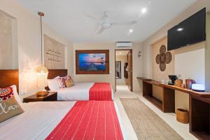 a hotel room with a bed and a flat screen tv at KAHATSA' boutique hotel in Tulum