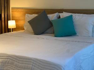 a white bed with two blue pillows on it at HOTEL 9.5 SAN FERNANDO in Cali