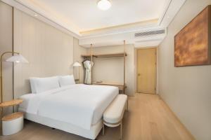 a bedroom with a large white bed and a table at 苏州山塘街华贸姑苏里酒店公寓 in Suzhou