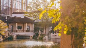 a garden with a pond in front of a building at 苏州山塘街华贸姑苏里酒店公寓 in Suzhou