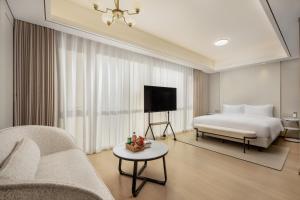 a bedroom with a bed and a couch and a tv at 苏州山塘街华贸姑苏里酒店公寓 in Suzhou