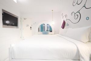 a white bedroom with a white bed and a tv at Dash Resort Langkawi in Pantai Cenang