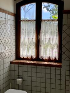 a bathroom window with white curtains in a bathroom at Fattoria Cirene in Follonica
