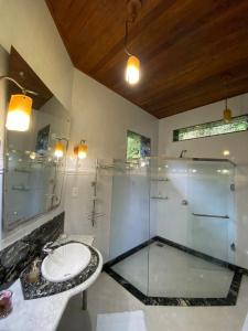 une salle de bain avec une douche en verre et un lavabo dans l'établissement Pousada Rocamadour, à Marechal Floriano 12 autres photos