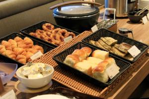 a buffet with trays of different types of bread and pastries at Richmond Hotel Yokohama Ekimae in Yokohama