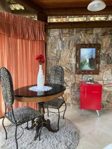 d'une table avec deux chaises et d'un vase avec des fleurs. dans l'établissement Pousada Rocamadour, à Marechal Floriano