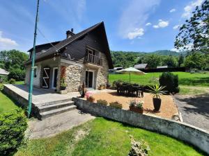 a small stone house with a patio and umbrella at Maison avec jardin près de Luchon in Cazaux-Layrisse