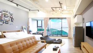 a bedroom with a bed and a couch and a large window at 光嶼海溫泉海景無邊際泳池豪華套房 in Hsin-hsing