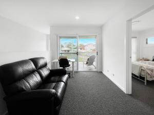 a living room with a leather couch and a bedroom at Coastline Cove - Modern Townhome Oasis in Shellharbour +27 photos