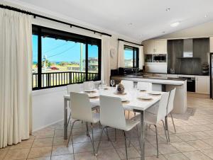 a dining room with a table and chairs and a kitchen at Family Getaway Opposite Warilla Beach in Lake Illawarra
