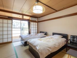 two beds in a room with a window at Kiso Mikawaya in Kiso