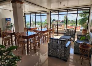 a restaurant with tables and chairs and windows at Nober Pension House City Center in Puerto Princesa City