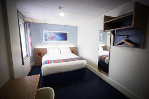 a small room with a bed and a table in it at Travelodge Belfast in Belfast