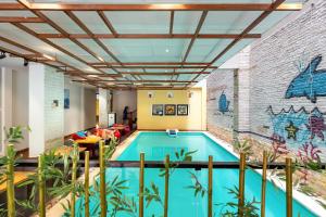 a swimming pool in a building with a mural at Harmony Old Town Hostel and Pool Bar in Hoi An
