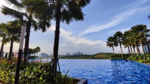 a swimming pool with palm trees in the foreground at Sunway Grid Loft Suite by Chill Lah Home in Iskandar Puteri
