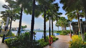 a walkway lined with palm trees next to a body of water at Sunway Grid Loft Suite by Chill Lah Home in Iskandar Puteri