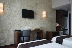 a hotel room with a desk and a television on the wall at LA Hotel in Tawau