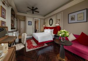 a bedroom with a white bed and a red couch at Hôtel de l'Amour Tam Đảo in Tam Ðảo