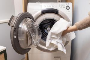 a woman is wiping a washing machine with a towel at Tokyu Stay Yotsuya Shinjuku in Tokyo