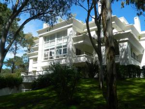 a white building with trees in front of it at Green Park en Uruguay in Punta del Este