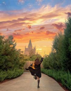 a woman is walking down a path with a castle in the background at Happy Dragon Universal Vacation Hotel - close to Universal Studio and Wanda Plaza,free shuttle to the Resort,Free Coffee,Laundry in Beijing