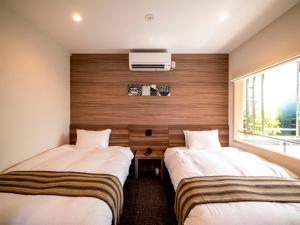two beds in a room with a window at HOTEL R9 Kujukuri "ex Casual Resort COFF Ichinomiya" in Ichinomiya