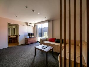 a room with a bed and a couch and a table at HOTEL R9 Kujukuri "ex Casual Resort COFF Ichinomiya" in Ichinomiya