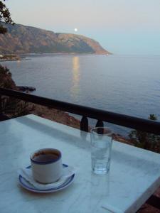 a cup of coffee sitting on a table next to a view of the ocean at Sweet Corner Masxali in Agia Roumeli
