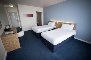 a hotel room with two beds and a desk at Travelodge Limerick Castletroy in Limerick