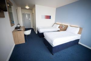 a hotel room with two beds and a desk at Travelodge Limerick Castletroy in Limerick