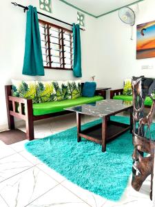 a living room with a green couch and a table at Wind&Waves Beach Apartment in Diani Beach