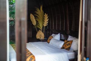 ein Bett mit weißen Laken und Kissen in einem Zimmer in der Unterkunft Villa Lumbung Sari - Tropical Balinese Experience in Canggu