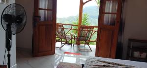 a room with a fan and a balcony with chairs at sunlit cottage ella in Ella