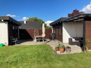 une arrière-cour avec une terrasse dotée d'une table et d'un parasol dans l'établissement Cozy Cottage Close To The Beach, à Bogense 8 autres photos