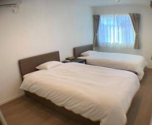 zwei Betten in einem Hotelzimmer mit weißen Laken in der Unterkunft スターレジデント in Inzai