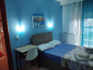 a blue bedroom with a bed and a table and a desk at Ester's Sea Side apartment in Neoi Epivates