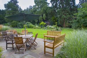 a patio with tables and chairs and an umbrella at Benslow Music Historic Stay in Hitchin in Hitchin