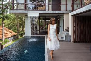 a woman in a white dress standing in front of a house at Villa Zolitude Resort & Spa - SHA Extra Plus in Chalong