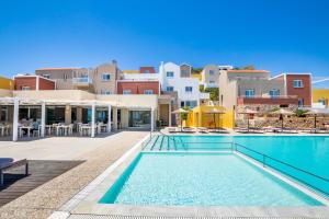 a swimming pool with tables and chairs and buildings at Apolis Beachscape Hotel in Amoopi