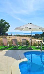 two chairs and an umbrella next to a swimming pool at Natua Apartment in Krvavica