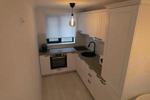 Una pequeña cocina con gabinetes blancos y un fregadero. en Apartament Cosmi Ari, en Băile Herculane